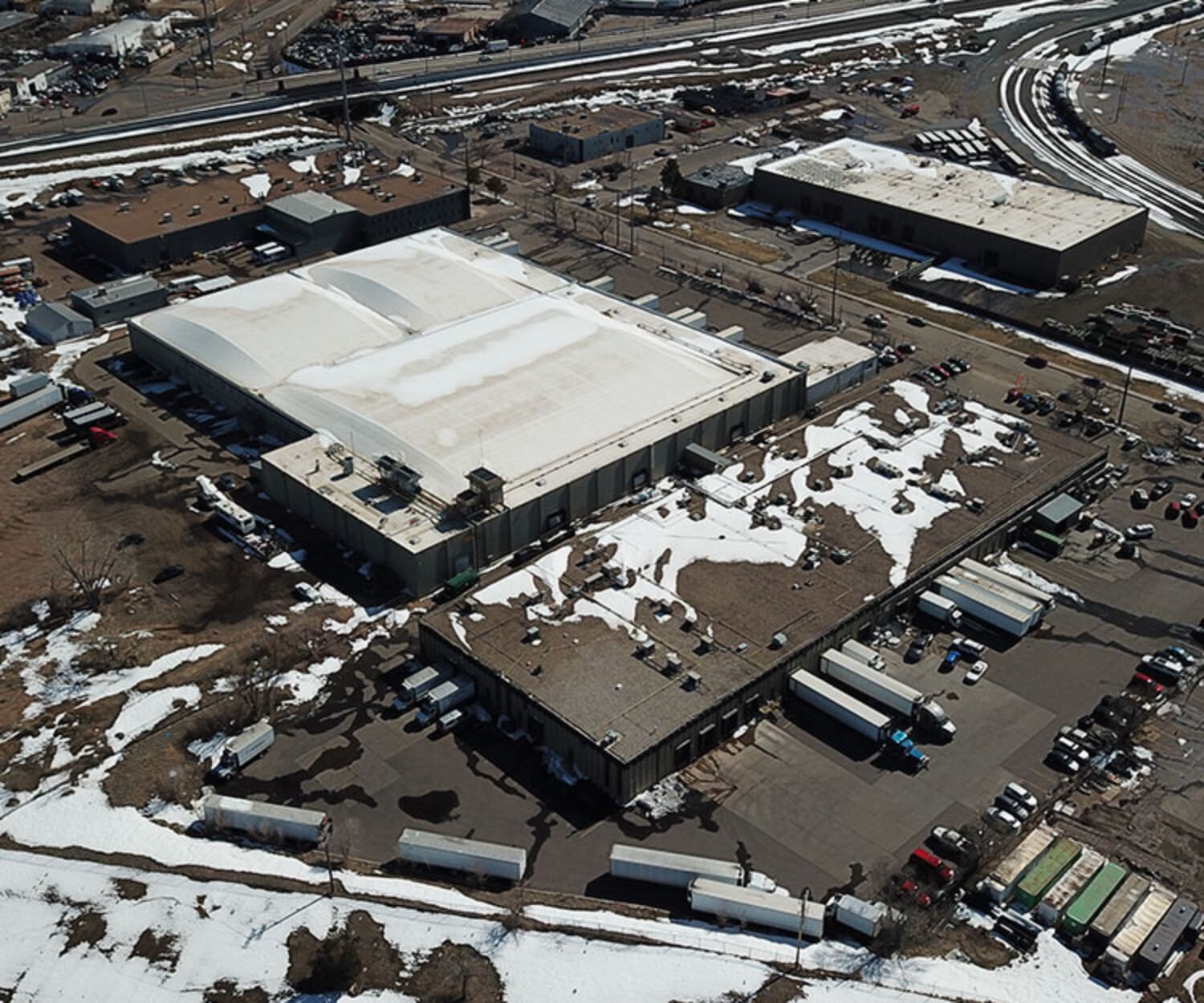 Industrial warehouse building in Colorado with snow on the roof and yard