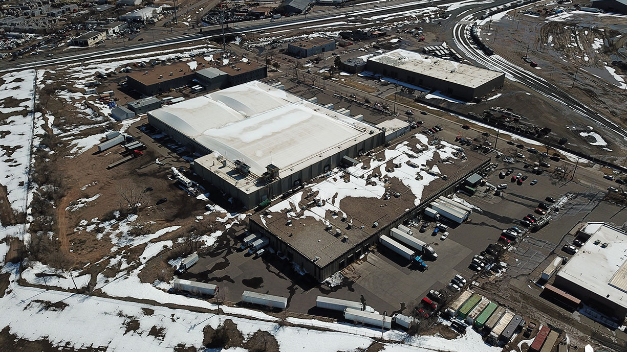 Industrial warehouse building in Colorado with snow on the roof and yard